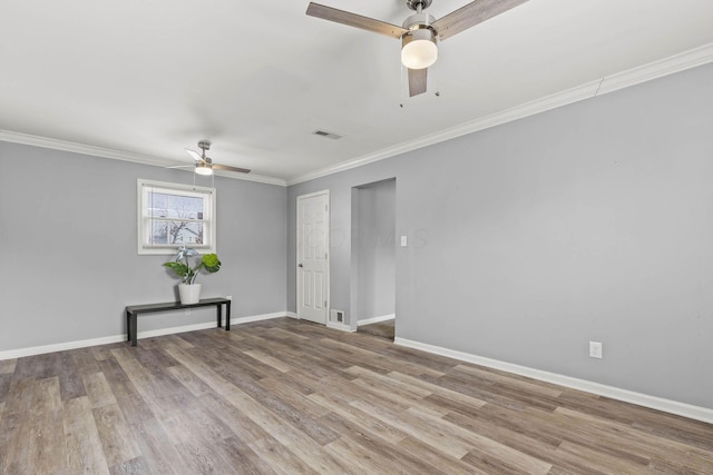 empty room with light wood-style floors, baseboards, visible vents, and crown molding