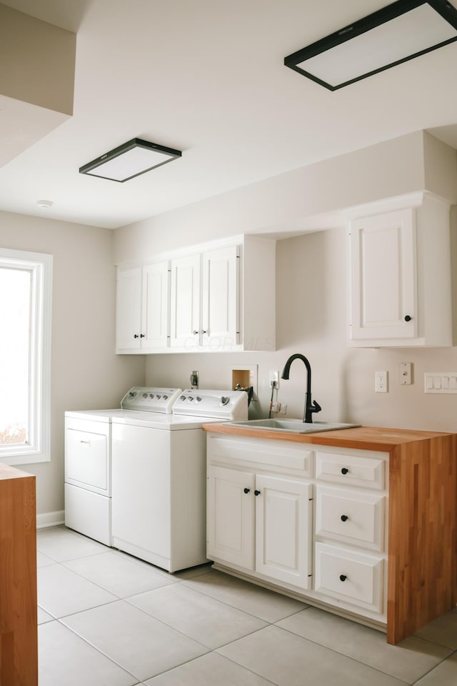 washroom featuring cabinet space, a sink, washing machine and clothes dryer, and light tile patterned floors