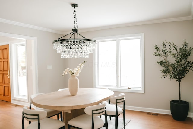 dining room with light wood-style floors, visible vents, ornamental molding, and baseboards