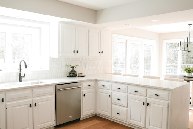 kitchen with white cabinets, dishwasher, a peninsula, and a sink