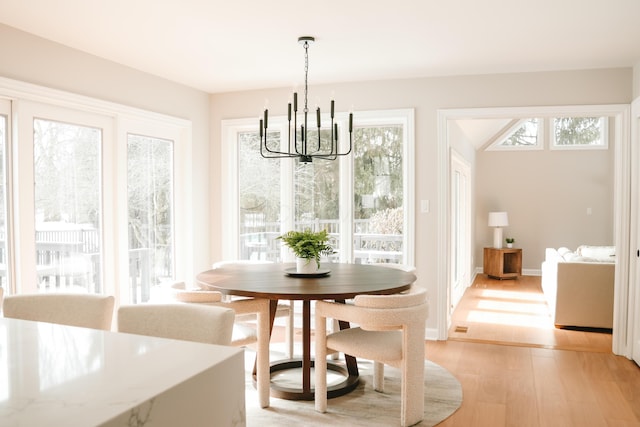 dining space featuring light wood-type flooring, baseboards, a chandelier, and a wealth of natural light