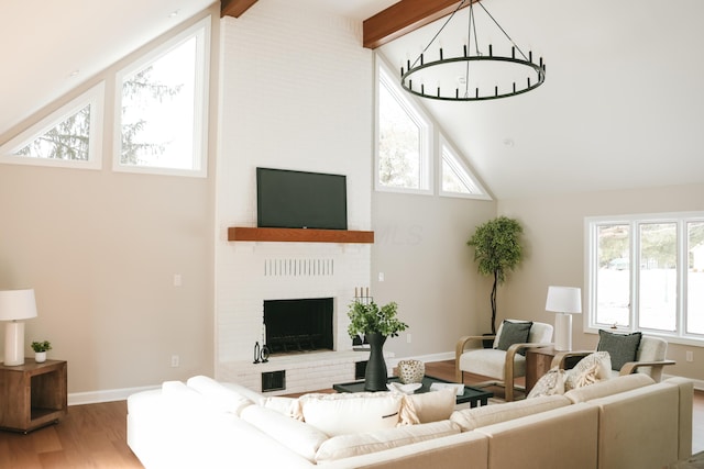 living room with baseboards, wood finished floors, beamed ceiling, a brick fireplace, and high vaulted ceiling