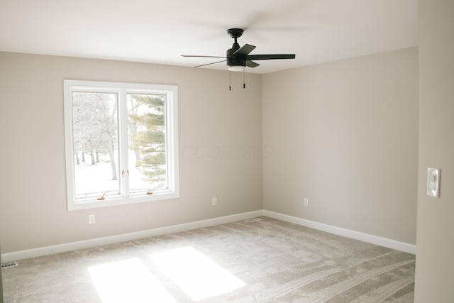 empty room featuring ceiling fan, baseboards, and light colored carpet