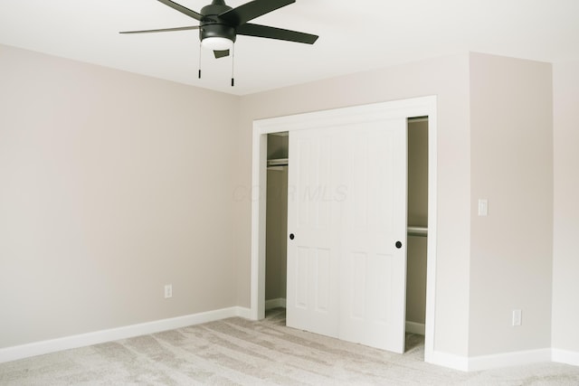 unfurnished bedroom featuring light carpet, a closet, a ceiling fan, and baseboards