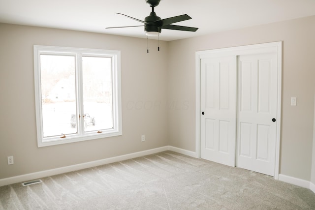 unfurnished bedroom with a closet, light carpet, and baseboards