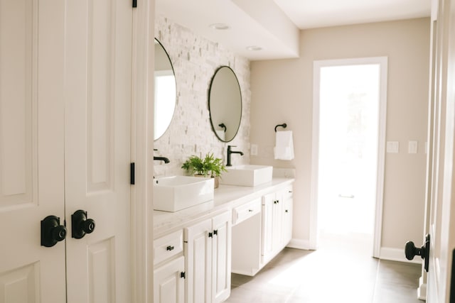 full bathroom featuring double vanity, a sink, and baseboards