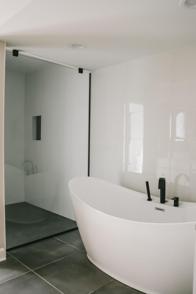 bathroom featuring a freestanding bath and tile patterned flooring