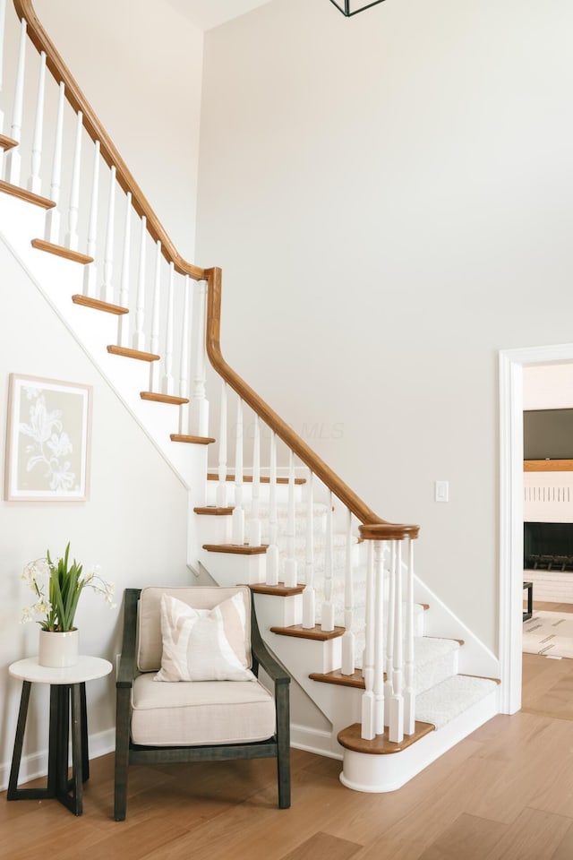 staircase with a towering ceiling, baseboards, and wood finished floors