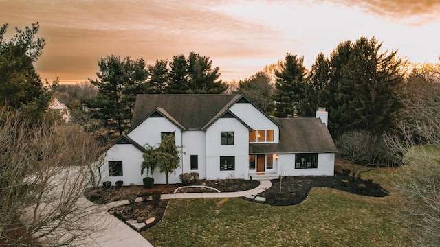 modern farmhouse style home featuring a chimney and a lawn