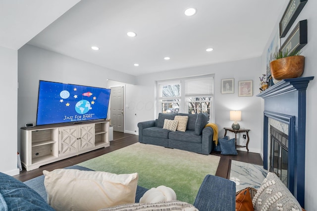 living area featuring baseboards, dark wood-type flooring, a glass covered fireplace, and recessed lighting