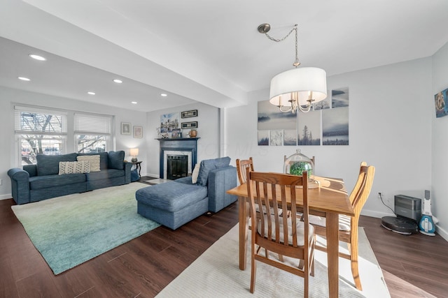 dining room with recessed lighting, dark wood-style flooring, a fireplace, baseboards, and an inviting chandelier