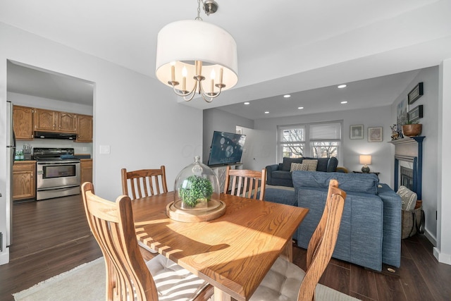 dining room featuring dark wood-style floors, recessed lighting, a fireplace, and a notable chandelier