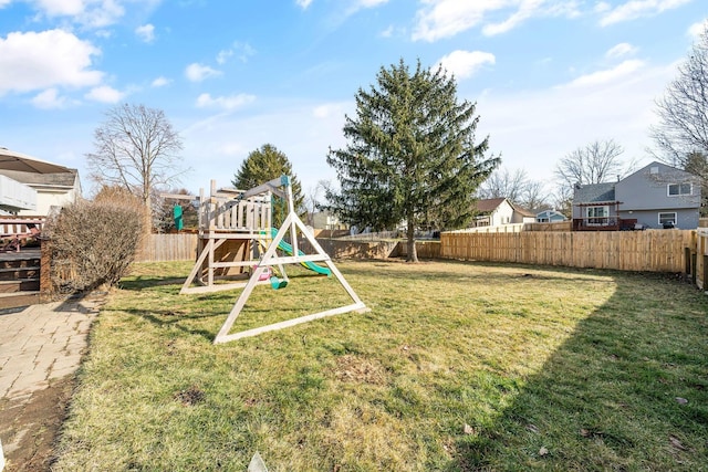 view of jungle gym featuring a lawn, a fenced backyard, and a residential view