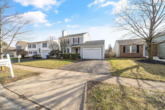 view of front of house with brick siding, a chimney, a front yard, a garage, and driveway