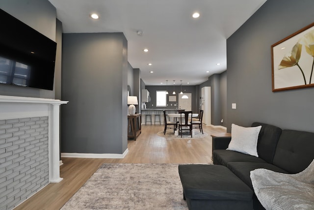 living room featuring light wood-type flooring, baseboards, and recessed lighting