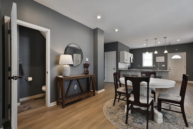 dining room with light wood finished floors, baseboards, and recessed lighting