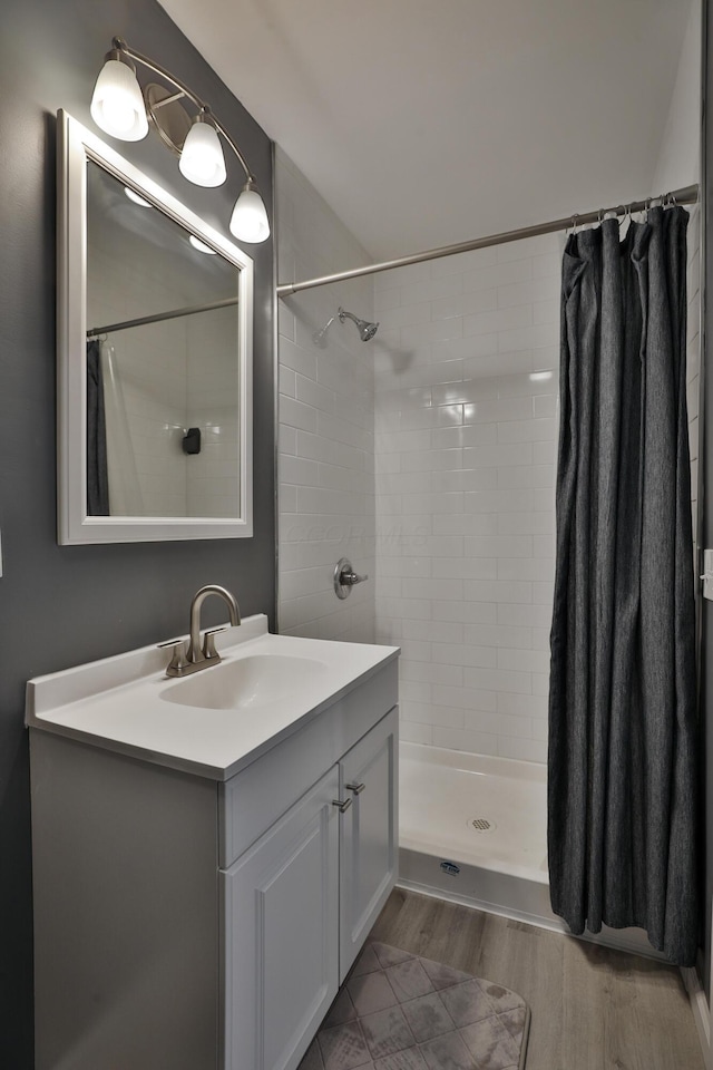 bathroom with tiled shower and vanity