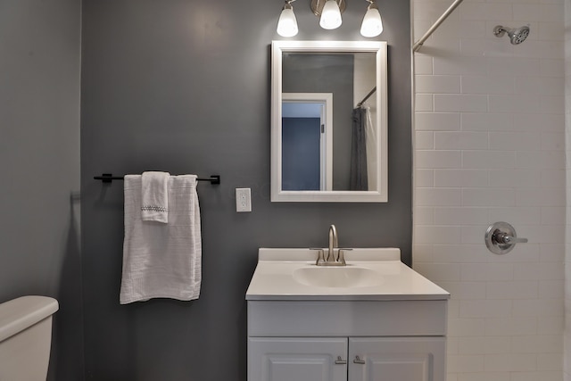 full bath featuring toilet, tiled shower, and vanity