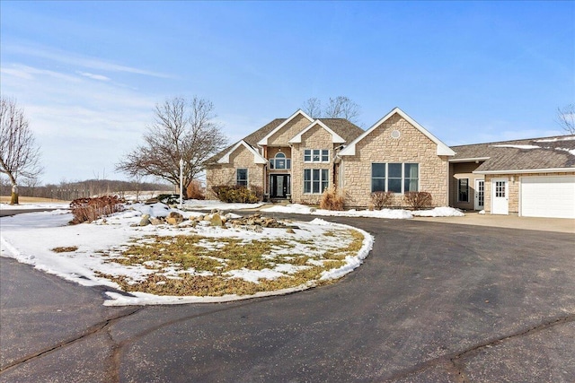 view of front of home with driveway, stone siding, and an attached garage