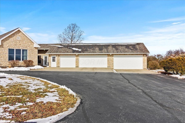 single story home featuring a garage and stone siding