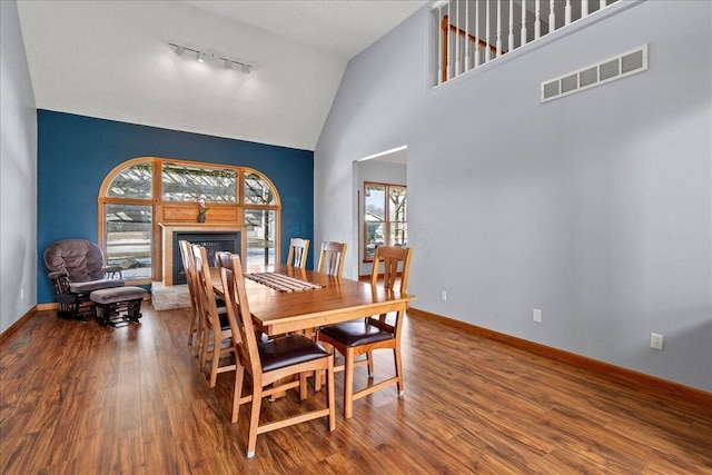 dining area featuring visible vents, a fireplace with raised hearth, baseboards, and wood finished floors