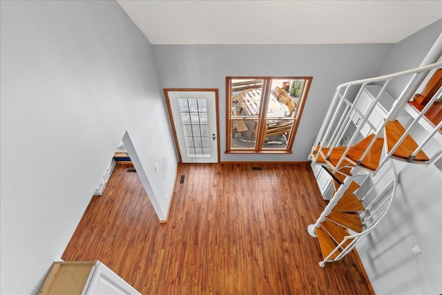 entrance foyer with visible vents, dark wood-type flooring, a textured ceiling, baseboards, and stairs