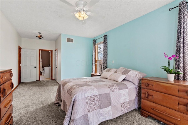 carpeted bedroom with a ceiling fan, visible vents, a textured ceiling, and ensuite bath