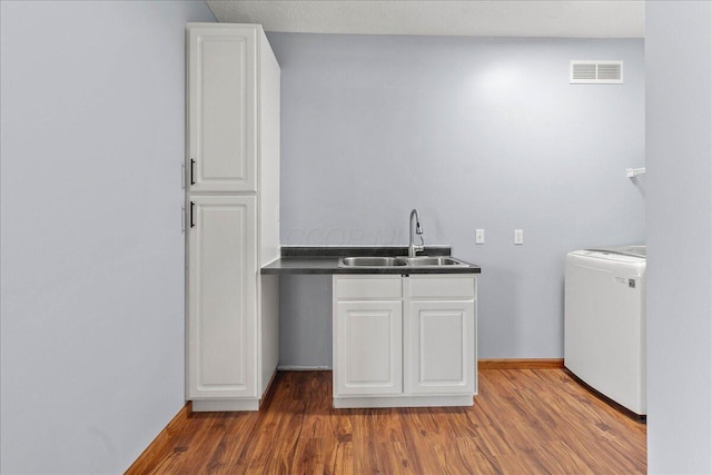 washroom with baseboards, visible vents, dark wood finished floors, washer / clothes dryer, and a sink