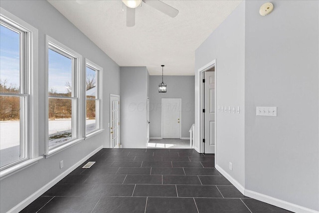 interior space featuring a textured ceiling, dark tile patterned floors, visible vents, and baseboards