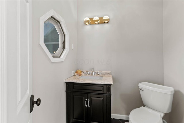 bathroom featuring vanity, toilet, and baseboards