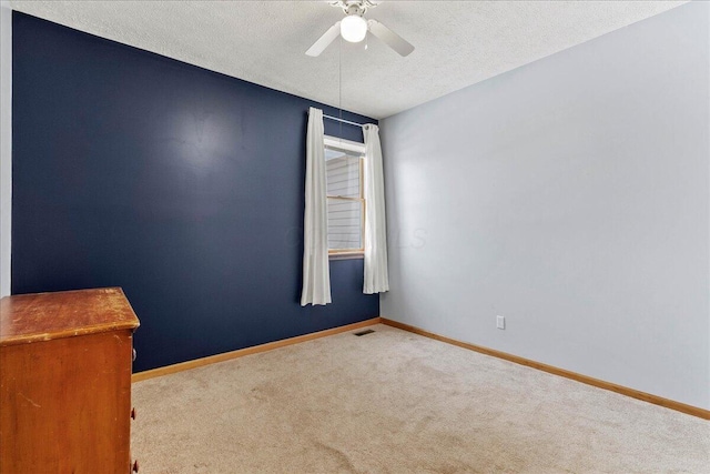 empty room with visible vents, light carpet, ceiling fan, a textured ceiling, and baseboards