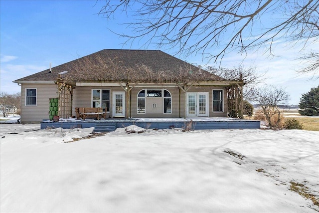 snow covered rear of property featuring covered porch