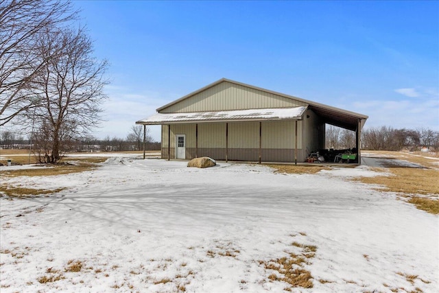 view of snowy exterior with a garage, a pole building, and a carport