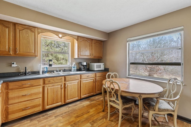 kitchen featuring white microwave, brown cabinetry, and dark countertops