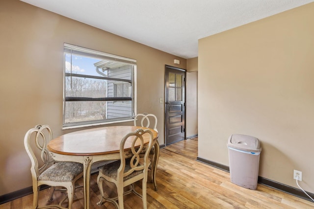 dining area featuring light wood-style floors, baseboards, and a textured ceiling