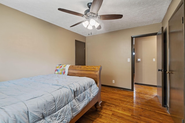 bedroom with ceiling fan, a textured ceiling, baseboards, and wood finished floors