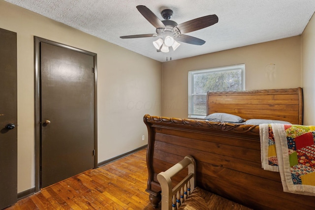 bedroom featuring a textured ceiling, wood finished floors, a ceiling fan, and baseboards