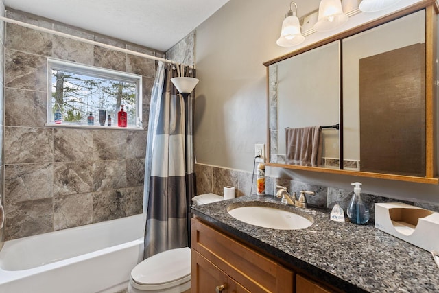 bathroom with shower / bath combination with curtain, tile walls, vanity, and toilet