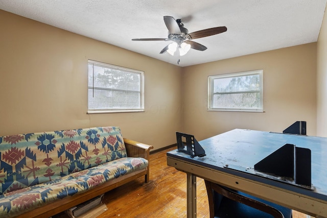 home office featuring ceiling fan, a textured ceiling, baseboards, and wood finished floors