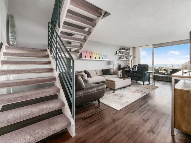 living area featuring dark wood-type flooring, expansive windows, and stairs