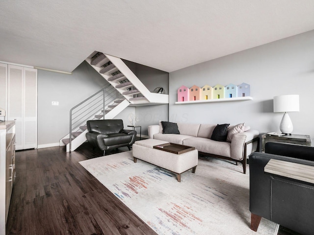 living area with stairs, dark wood-style flooring, and baseboards