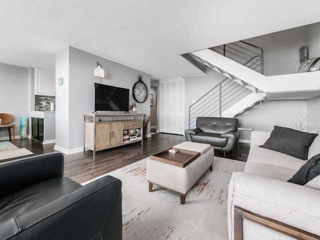 living room featuring stairway, baseboards, and wood finished floors