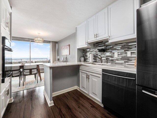 kitchen featuring a peninsula, black dishwasher, white cabinets, and freestanding refrigerator