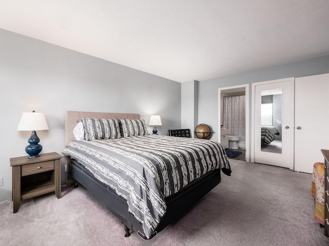 bedroom with ensuite bathroom and light colored carpet