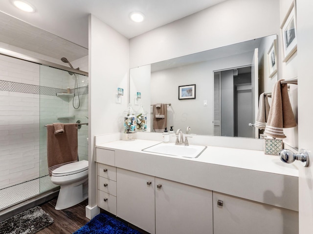 bathroom featuring recessed lighting, toilet, a stall shower, vanity, and wood finished floors