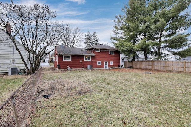 back of house with a yard, central AC unit, and fence