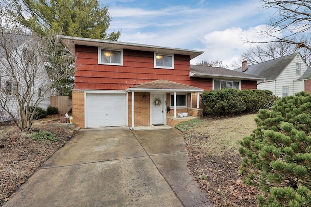 split level home featuring a garage, concrete driveway, brick siding, and fence