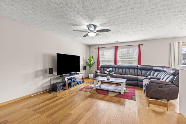 living area with ceiling fan, a textured ceiling, baseboards, and wood finished floors