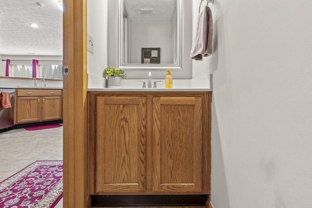 bathroom with a sink, tile patterned flooring, visible vents, and a textured ceiling