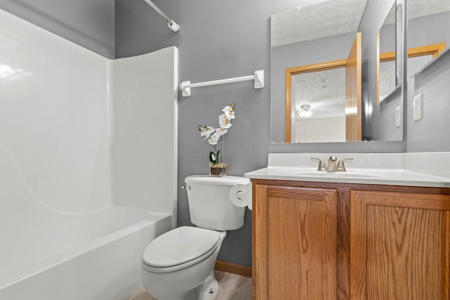 full bath with toilet, bathtub / shower combination, a textured ceiling, and vanity